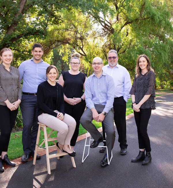 Evolve Accounting Team l enjoying the sunshine in the outside, surrounded by a garden you can see seven team members all smiling and facing the camera.